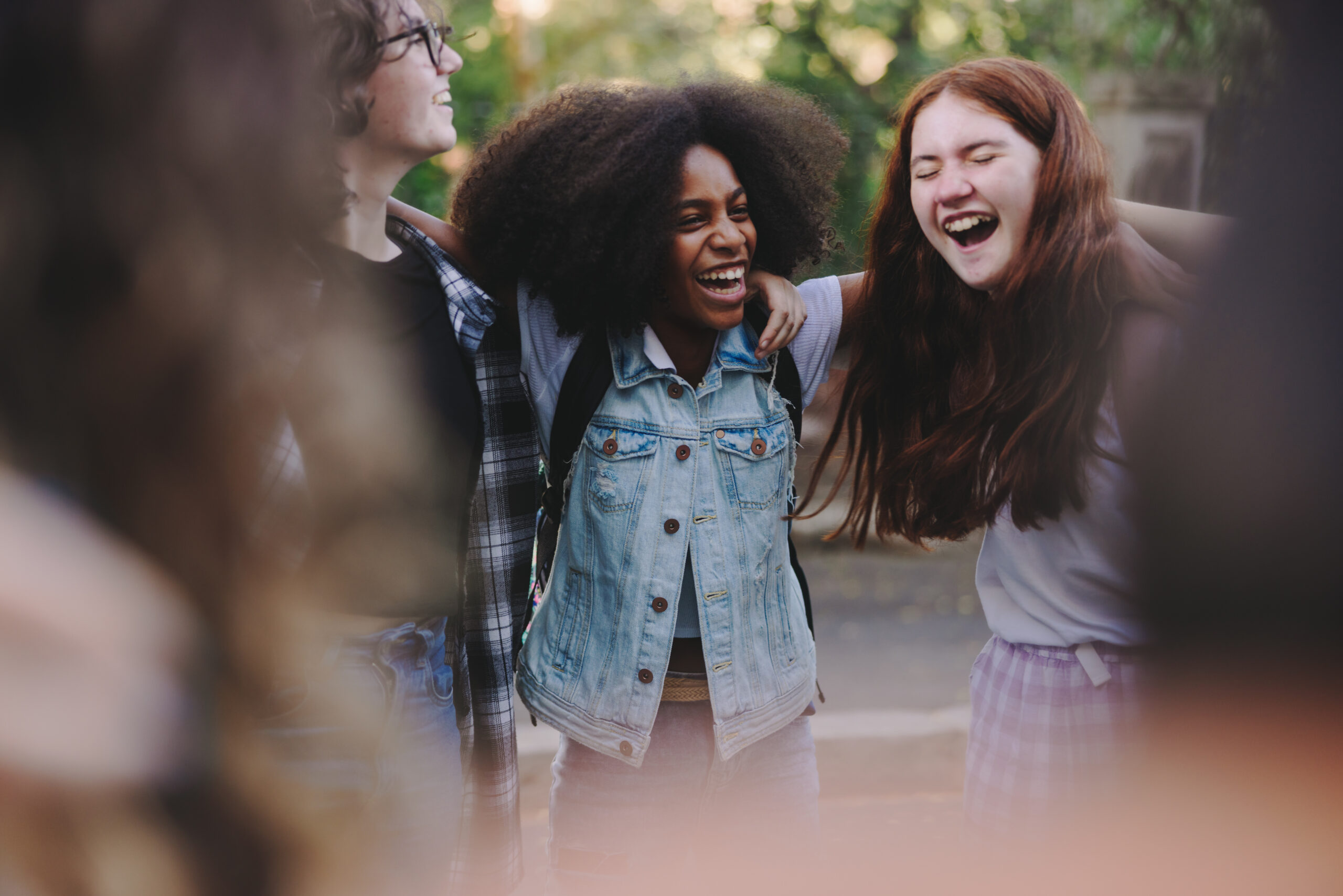 Happy teenage school kids embracing each other while standing in a circle. Group of multicultural young people in a huddle.