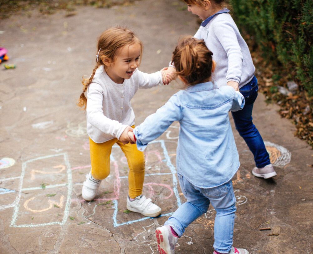 Toddler friends playing hopscotch outdoors